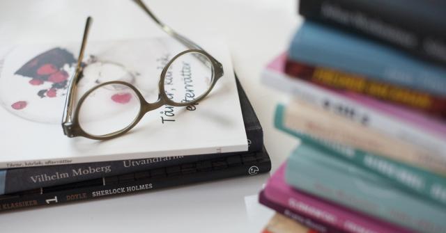 Läsglasögon och en hög med böcker